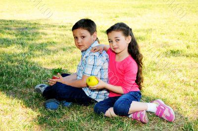 The boy with the girl play sitting on a grass