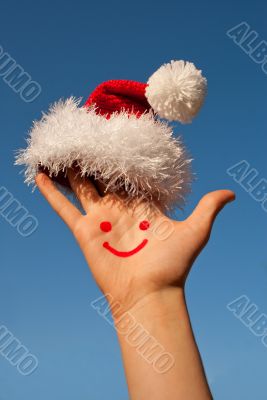 Human`s palm with smile on it wearing Santa`s hat