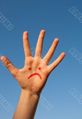 Human`s palm with unhappy smiley drawn on it