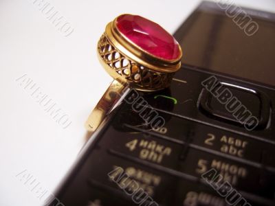 Mobile phone and golden ring with red stone