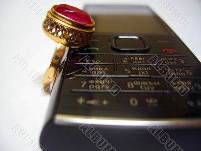 Mobile phone and golden ring with red stone