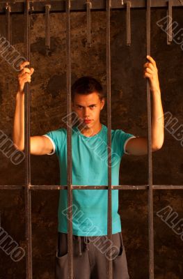 Man with hands tied with rope behind the bars