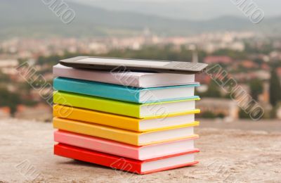 Stack of colorful books with e-book reader