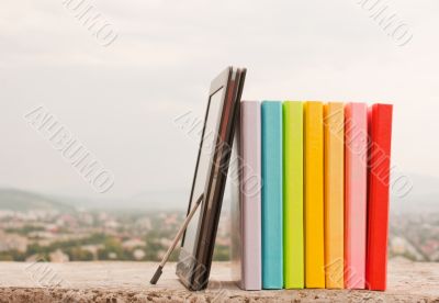 Stack of colorful books with e-book reader