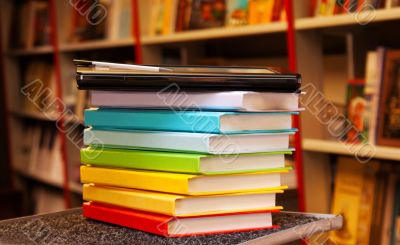 Stack of colorful books with e-book reader