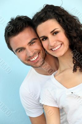 Cheerful couple in front of blue wall