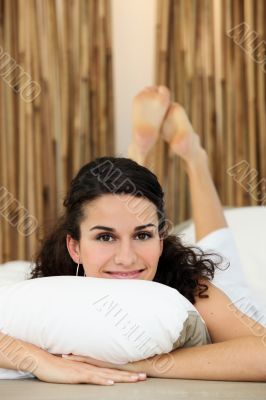 Young woman smiling laid on a bed