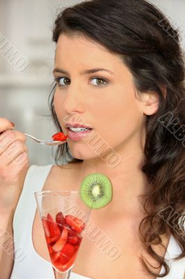 young woman eating fruit salad