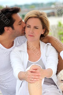 Couple sat together outdoors with small dog