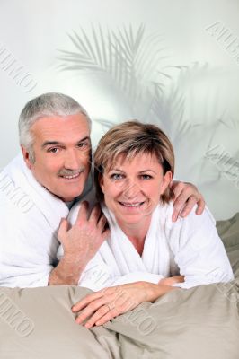 Mature couple in bathrobes on a bed