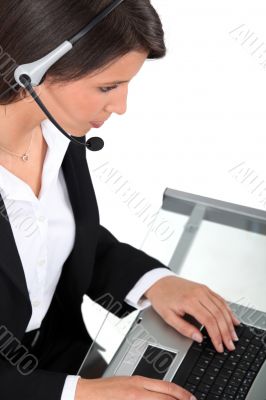 Young woman wearing a headset typing at a keyboard