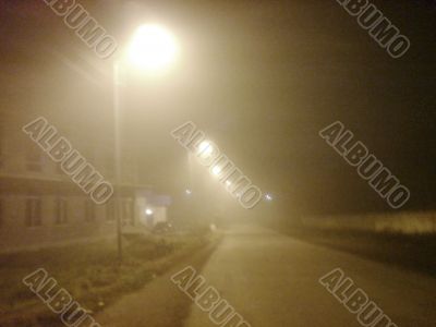 Fog laying over town. Street lamps in mist