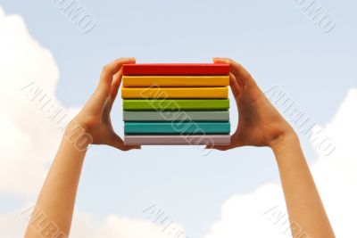 Hands holding colorful hard cover books