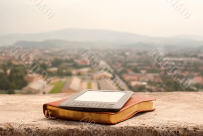 E-book reader laying on the book outdoors
