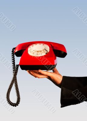 Hand holding an old fashioned red phone