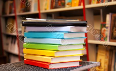 Stack of colorful books with e-book reader