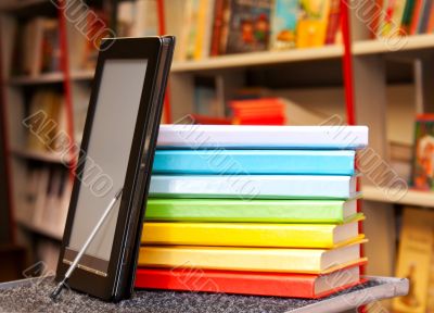 Stack of colorful books with e-book reader