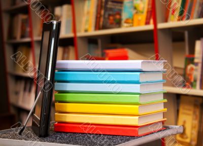 Stack of colorful books with e-book reader