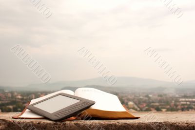 E-book reader laying on the book outdoors