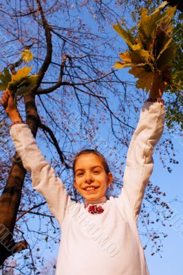 Girl playing with leaves at fall time