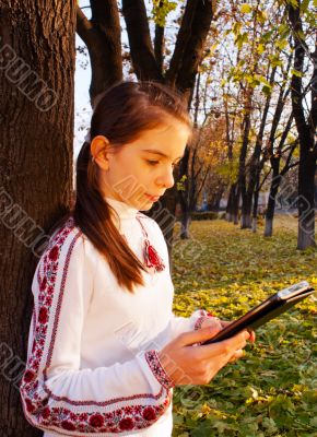 Teen girl with e-book reader in a park