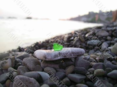 Green glass laying on the sea shore