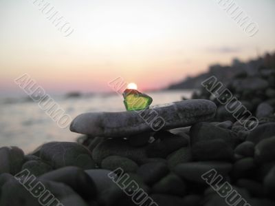 Green glass laying on the sea shore