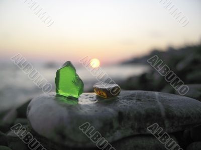 Green and orange glass laying on the sea shore