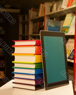 Stack of colorful books and electronic book reader