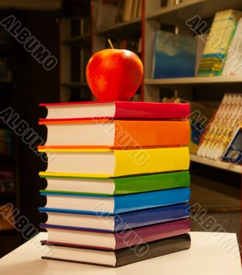 Pile of colorful books with an apple on it