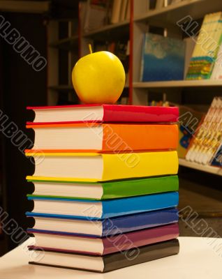 Pile of colorful books with an apple on it