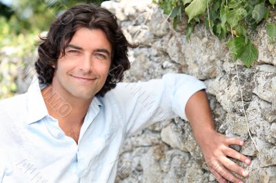 man leaning against an old stone country wall