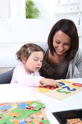 Mother and young daughter doing jigsaw puzzles