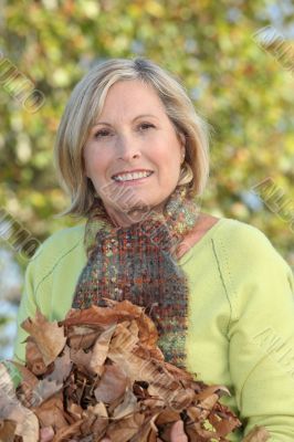 Woman with an armful of autumnal leaves