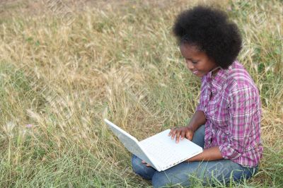 Young woman using a laptop in a field