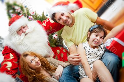 Happy family embracing and sitting on the floor in front of Christmas tree.