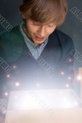 Portrait of young man opening gift box. He is happy.