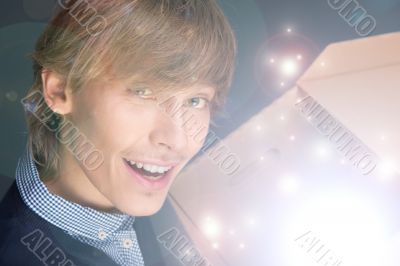 Portrait of young man opening gift box. He is happy. .