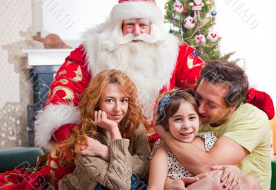 Happy family embracing and sitting on the floor in front of Chri