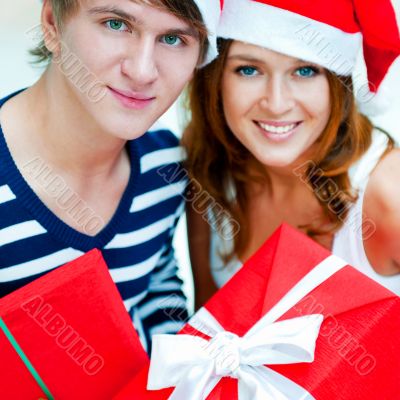 Young happy couple in Christmas hats standing together and holdi