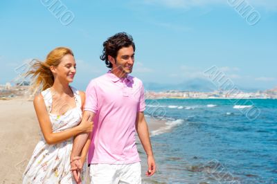 Couple at the beach holding hands and walking. Sunny day, bright