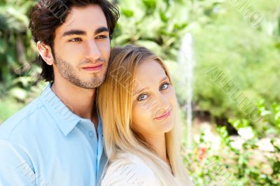 Portrait of love couple embracing outdoor in park looking happy