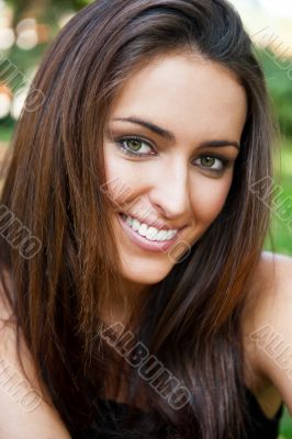 Portrait of smiling young girl sitting on grass in the forest an