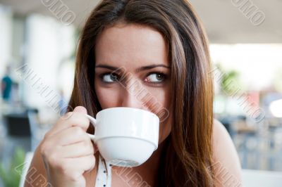 Closeup portrait of a pretty young female having a cup of coffee