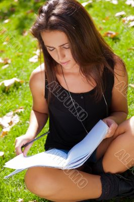 Portrait of a beautiful young female student sitting outdoor at 