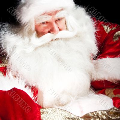 Santa sitting at the Christmas room and looking into the sack