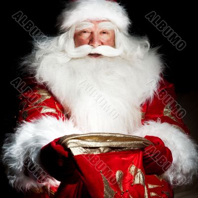 Santa sitting at the Christmas room and looking into the sack