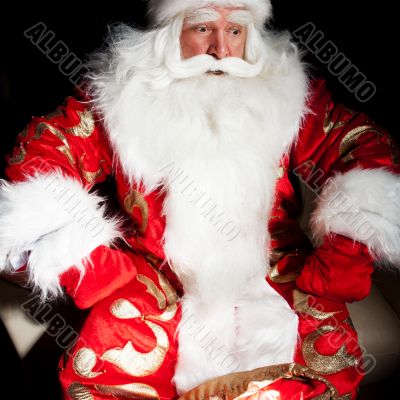 Santa sitting at the Christmas room and looking into the sack