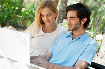 Young couple working on laptop and smiling while sitting relaxed