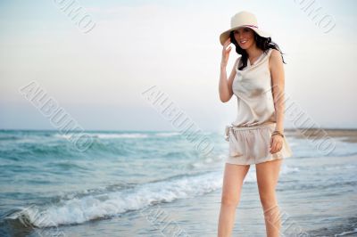 Smiling young woman wearing a straw hat and having fun at the be